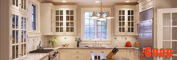 A kitchen with white cabinets has a picture window.