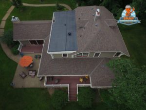 An aerial view of a large home with a brown shingle roof.