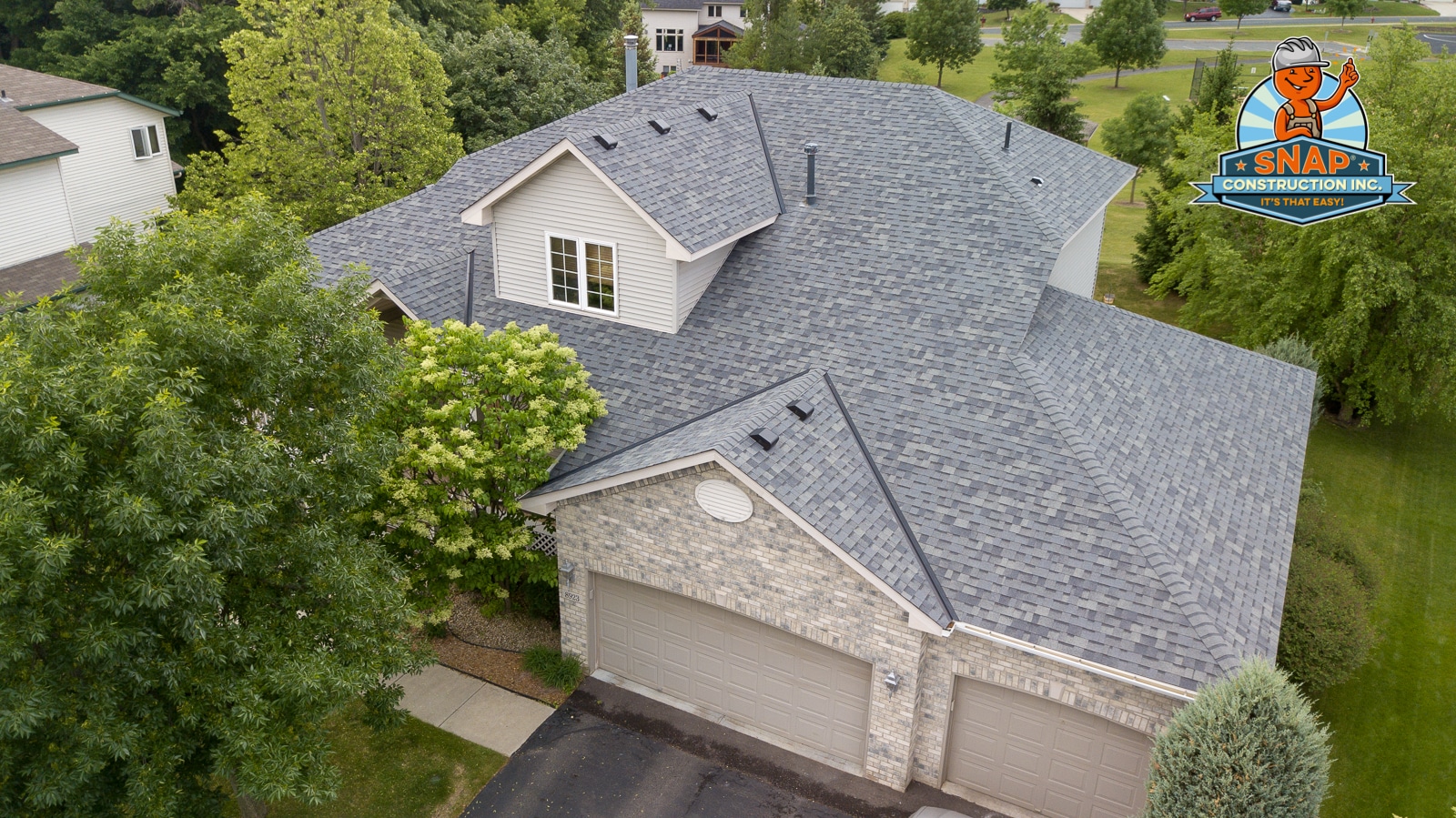 Aerial view of gray asphalt roofing on a suburban home in Bloomington MN, installed by Snap Construction with clean lines and vents