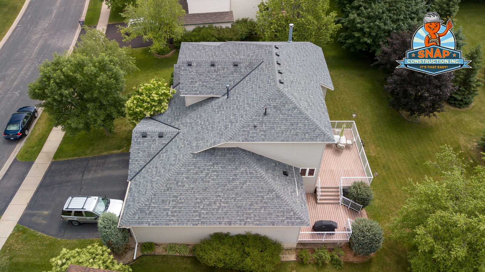 Aerial view of Bloomington MN home with new gray shingle roof and deck, showcasing Snap Construction roof leak repair quality