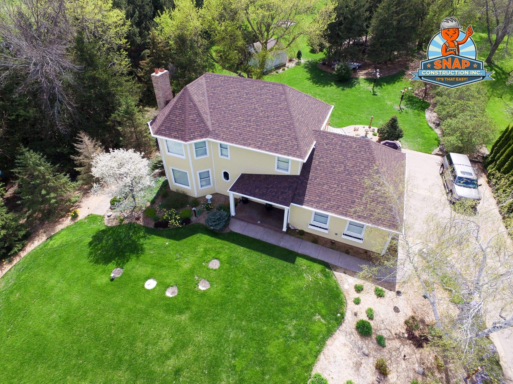 Aerial view of a yellow two-story home with new brown shingle roof by Snap Construction, best roofing contractor in Bloomington MN