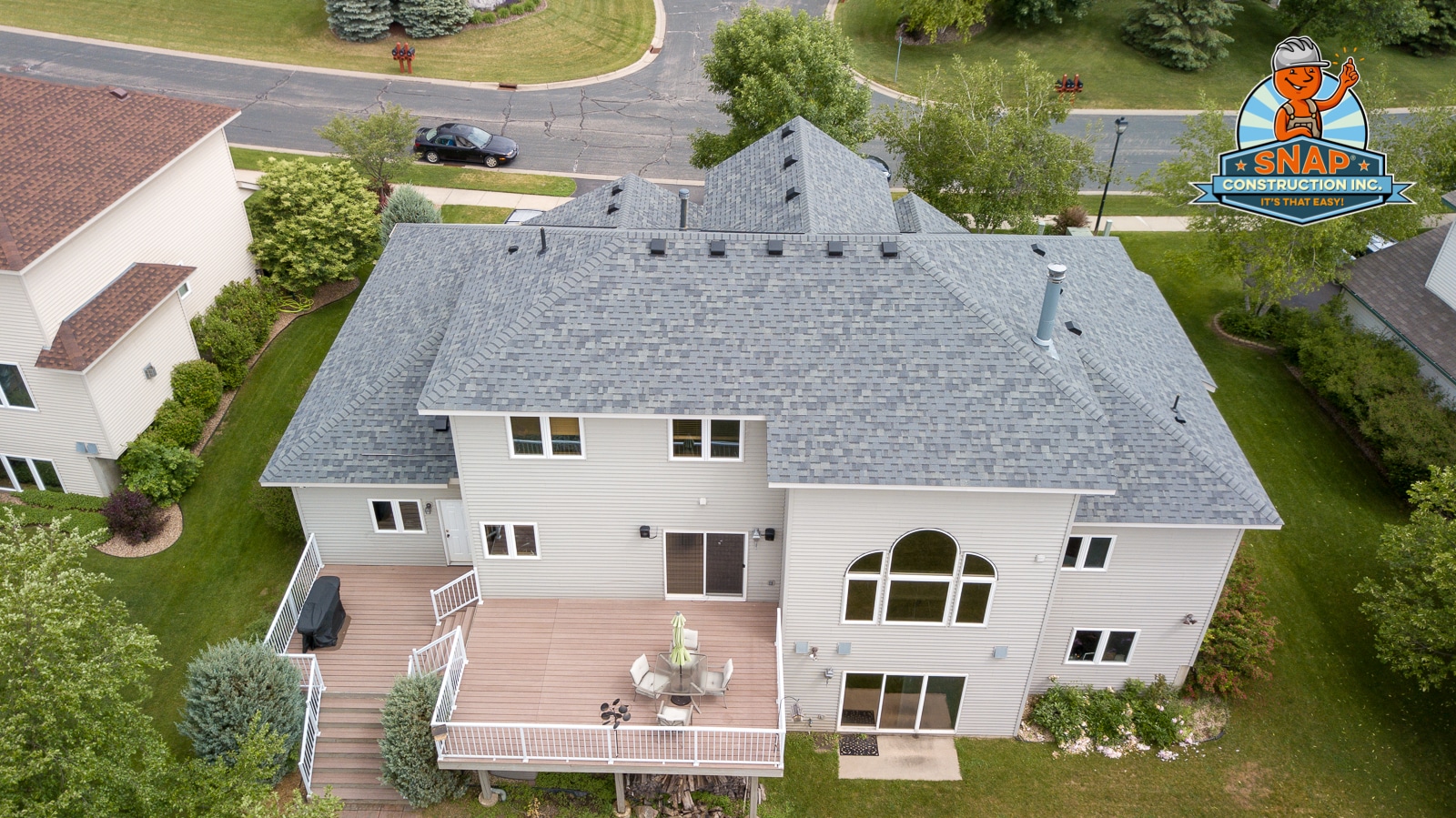 Aerial view of suburban home with gray asphalt shingle roof and deck after emergency roof repair by Snap Construction in Bloomington MN