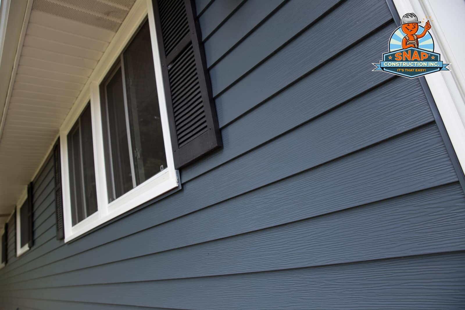 Blue horizontal lap siding with white-trim windows and black shutters installed by Snap Construction, siding company in Bloomington MN